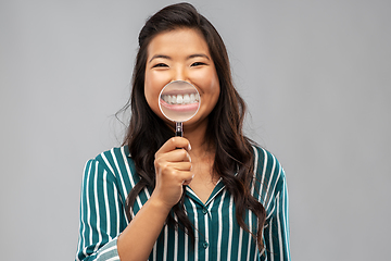 Image showing asian woman shows teeth through magnifying glass