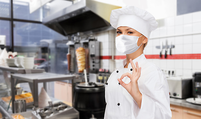 Image showing female chef in mask showing ok sign at kitchen