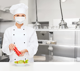 Image showing female chef in mask cutting vegetables at kitchen