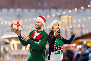 Image showing happy couple in christmas sweaters with gifts