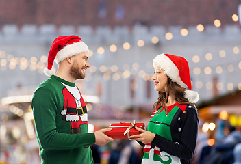 Image showing happy couple in christmas sweaters with gift box