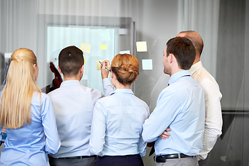 Image showing business team with sticky notes on glass at office