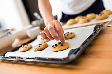 Image showing Woman adding chocolate bean on cookies