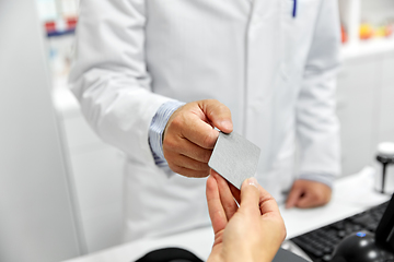 Image showing close up of hand giving bank card to pharmacist