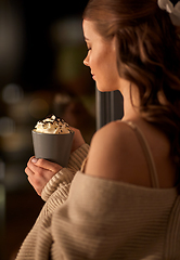 Image showing woman holding mug with whipped cream at night