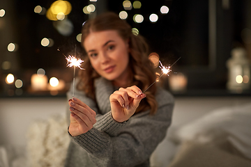 Image showing happy young woman with sparklers in bed at home