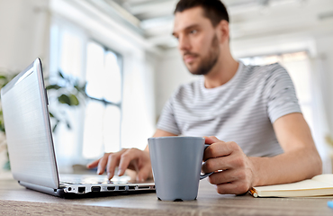 Image showing man with laptop drinking coffee at home office