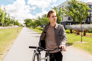 Image showing young man with bicycle walking along city street