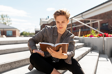 Image showing young man or teenage boy reading book in city