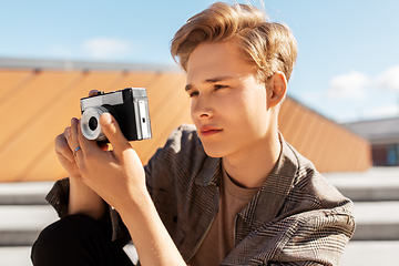 Image showing young man with camera photographing in city