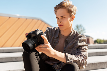 Image showing young man with camera photographing in city