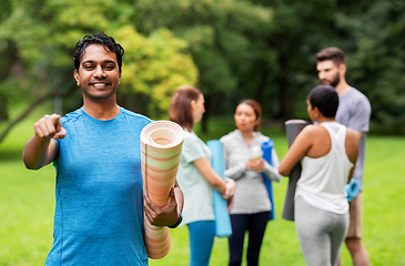 Image showing happy man with yoga mat pointing finger to camera