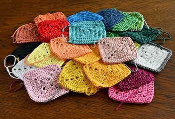 Image showing colorful knitted squares on the wooden background