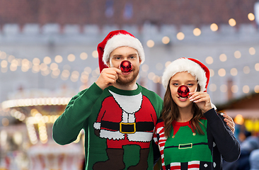 Image showing happy couple in christmas sweaters and santa hats