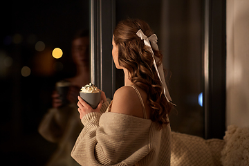 Image showing woman holding mug with whipped cream at night