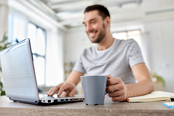 Image showing happy man with laptop drinking coffee at home