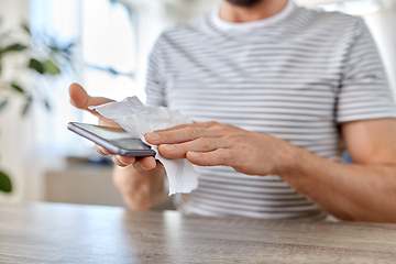 Image showing man cleaning phone with wet wipe at home office