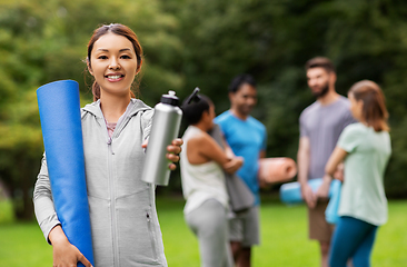 Image showing smiling woman with yoga mat and bottle at park