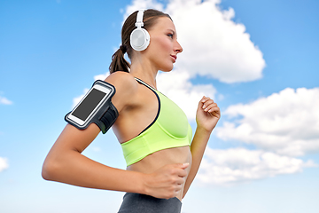 Image showing woman with headphones and smartphone running