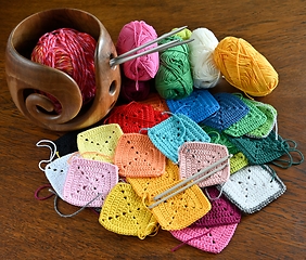 Image showing colorful knitted squares, skeins of wool and a wooden yarn bowl