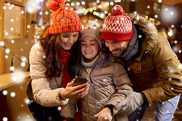 Image showing happy family with smartphone at christmas market