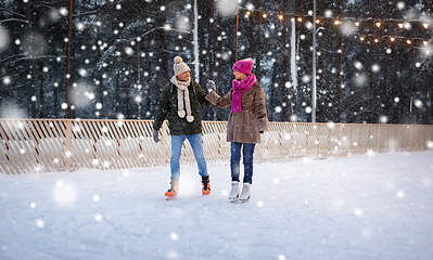 Image showing happy couple holding hands on skating rink