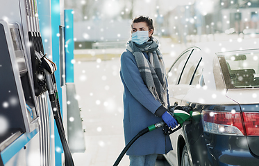 Image showing woman in mask filling her car at gas station