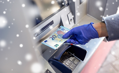 Image showing hand in medical glove with money at atm machine