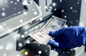 Image showing hand in medical glove with money at atm machine