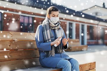 Image showing woman in mask spraying hand sanitizer outdoors