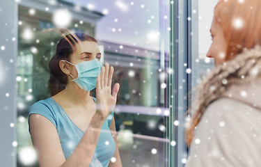 Image showing ill woman in mask looking at friend through window