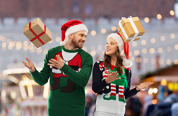 Image showing happy couple in christmas sweaters with gifts