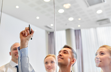 Image showing man with marker writing on glass wall at office