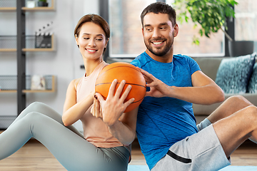 Image showing happy couple exercising with ball at home