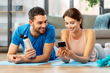 Image showing happy couple with smartphone after sports at home