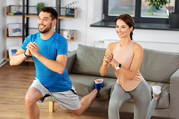 Image showing happy couple exercising and doing squats at home