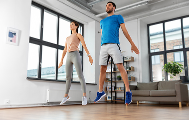 Image showing happy couple exercising and jumping at home