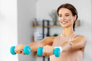 Image showing happy woman with dumbbells exercising at home