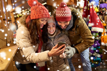 Image showing happy family with smartphone at christmas market