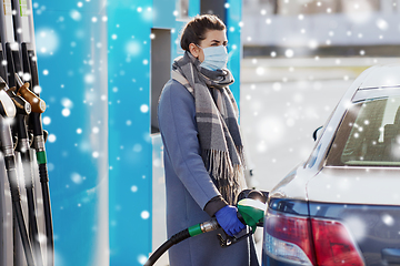 Image showing woman in mask filling her car at gas station