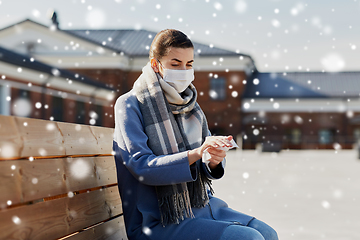 Image showing woman in mask cleaning hands with antiseptic wipe