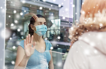 Image showing ill woman in mask looking at friend through window