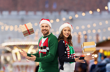 Image showing happy couple in christmas sweaters with gifts