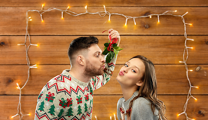 Image showing happy couple kissing under mistletoe on christmas