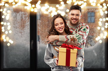 Image showing happy couple in christmas sweaters with gift box