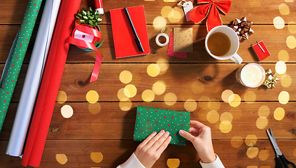 Image showing hands wrapping christmas gift into paper at home