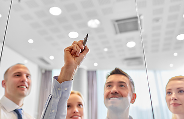 Image showing man with marker writing on glass wall at office