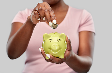 Image showing close up of woman with coin and piggy bank