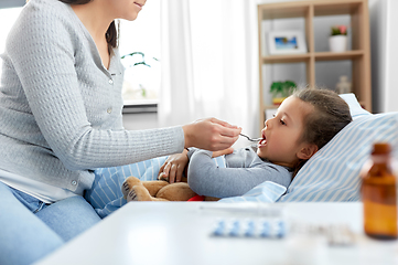 Image showing mother giving cough syrup to sick daughter