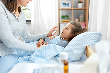 Image showing mother with oral spray treats sick little daughter